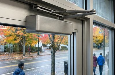 Hydraulic overhead door closer on an aluminum and glass storefront door in autumn